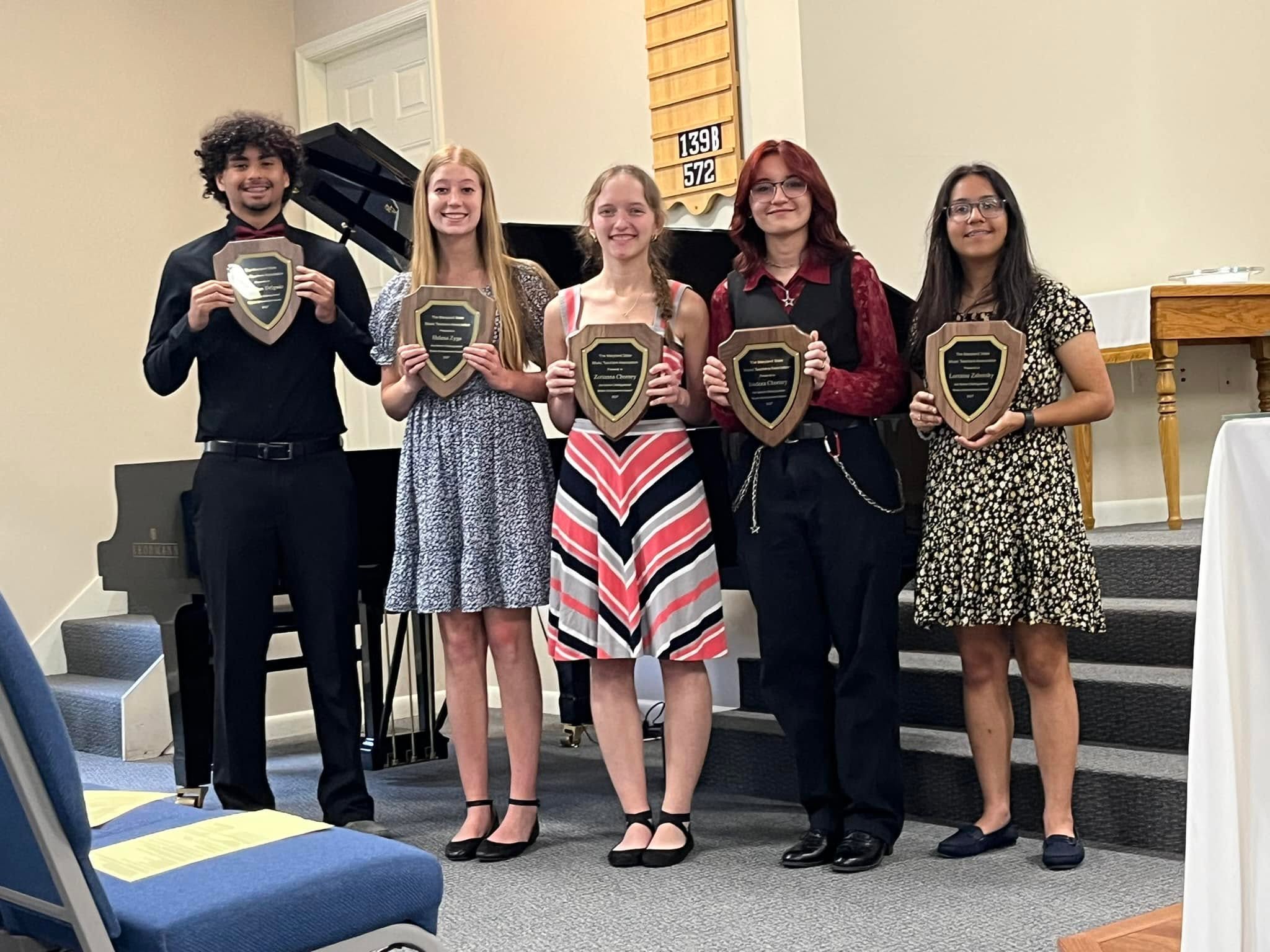 Piano students holding achievement awards