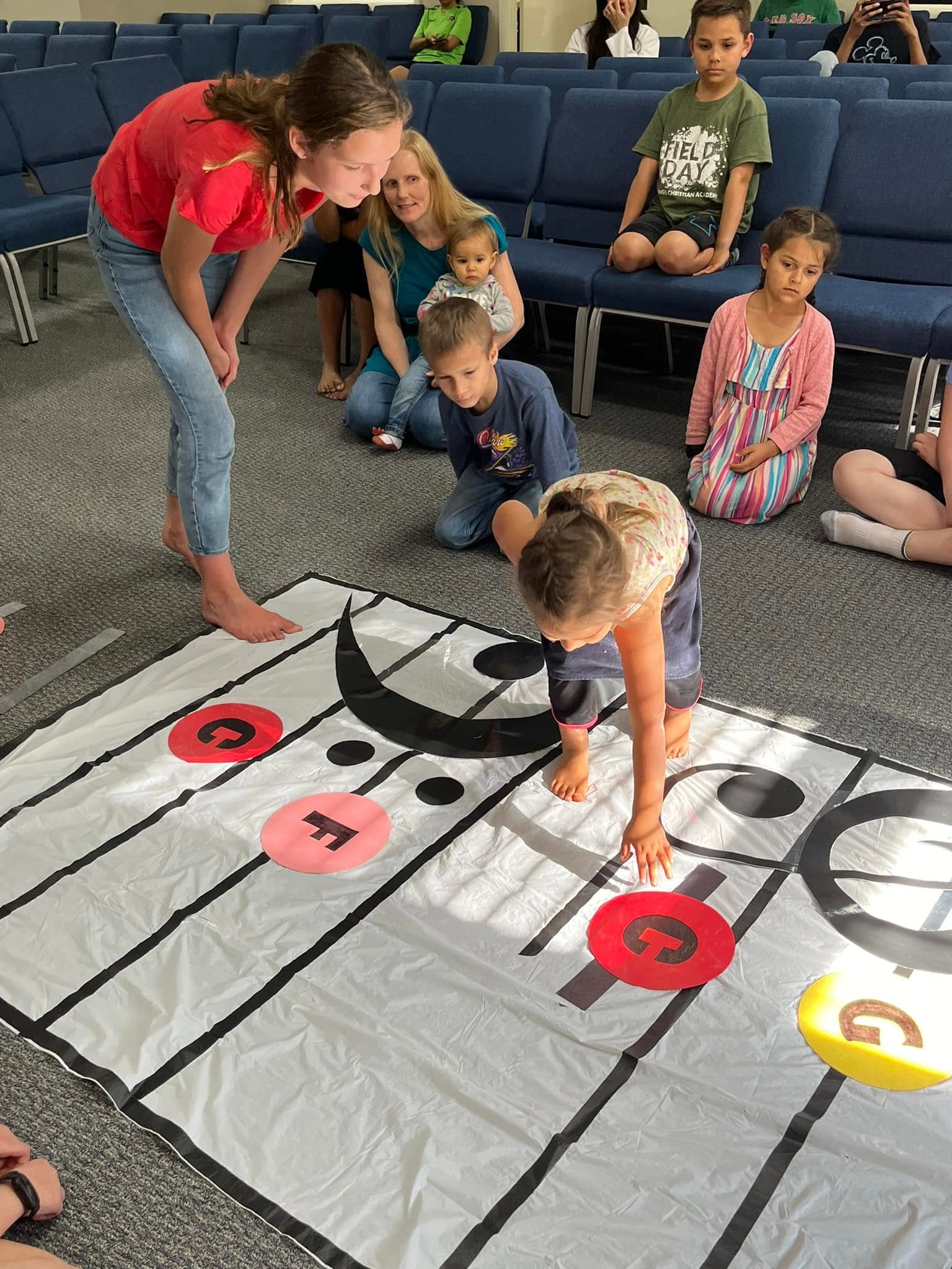 Children playing a music game on a large floor staff