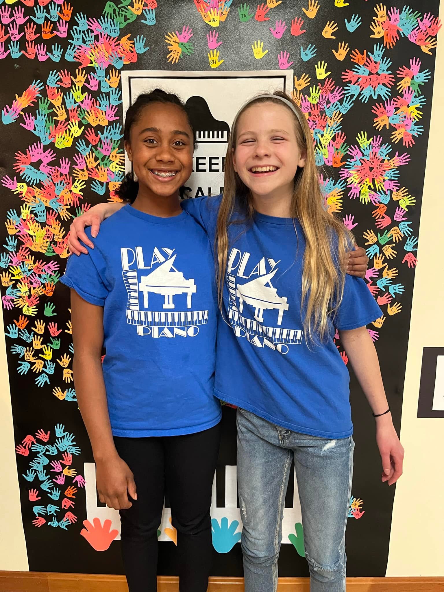 Two smiling piano students